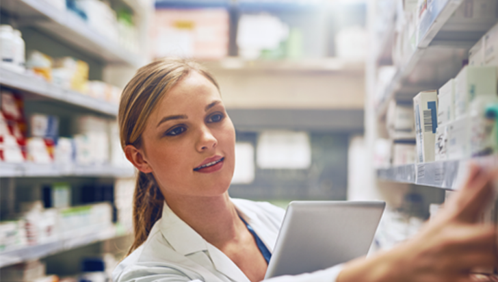 A pharmacist reaching for medication on a pharmacy shelf